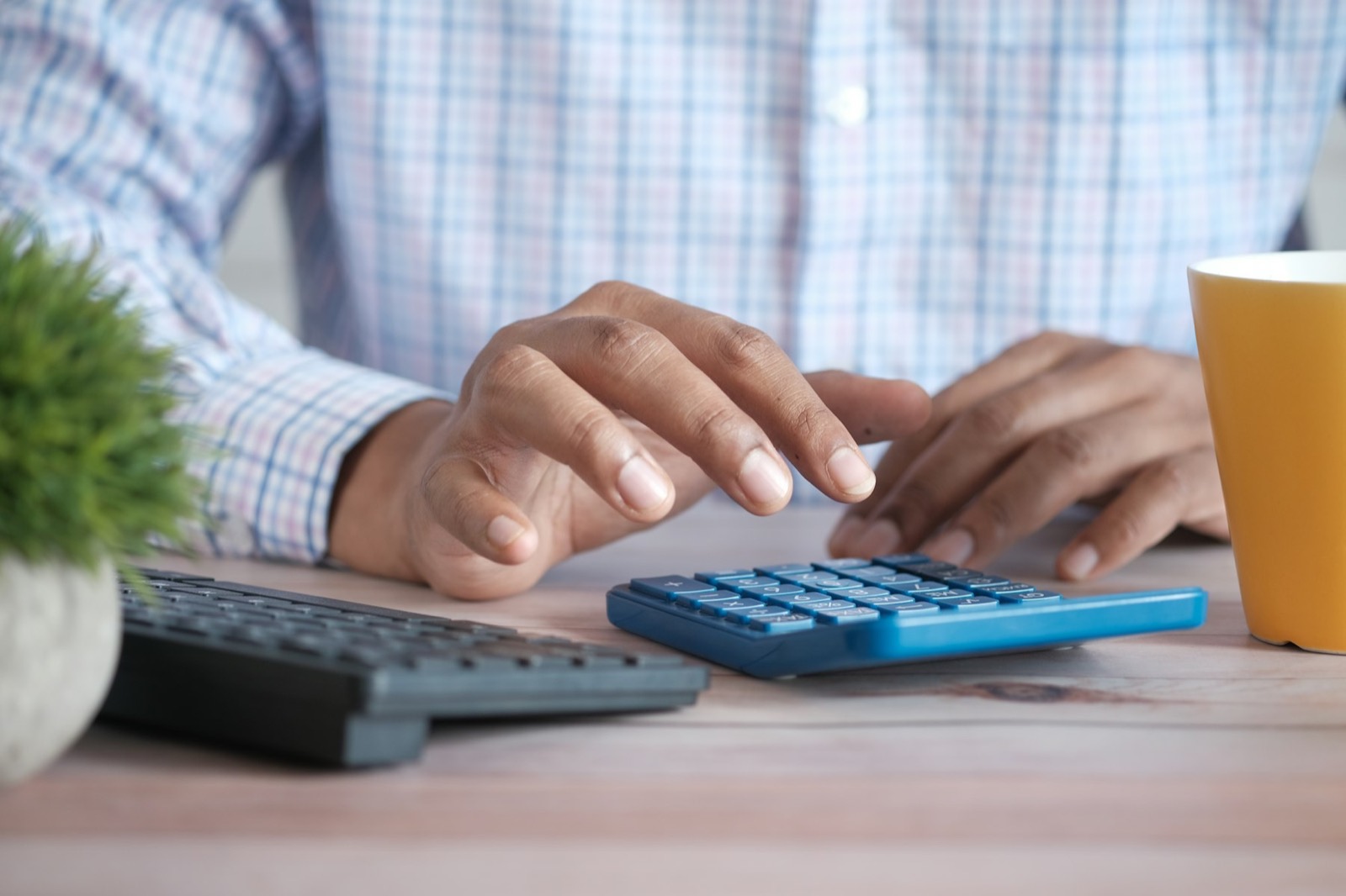 Hands working a calculator at a desk