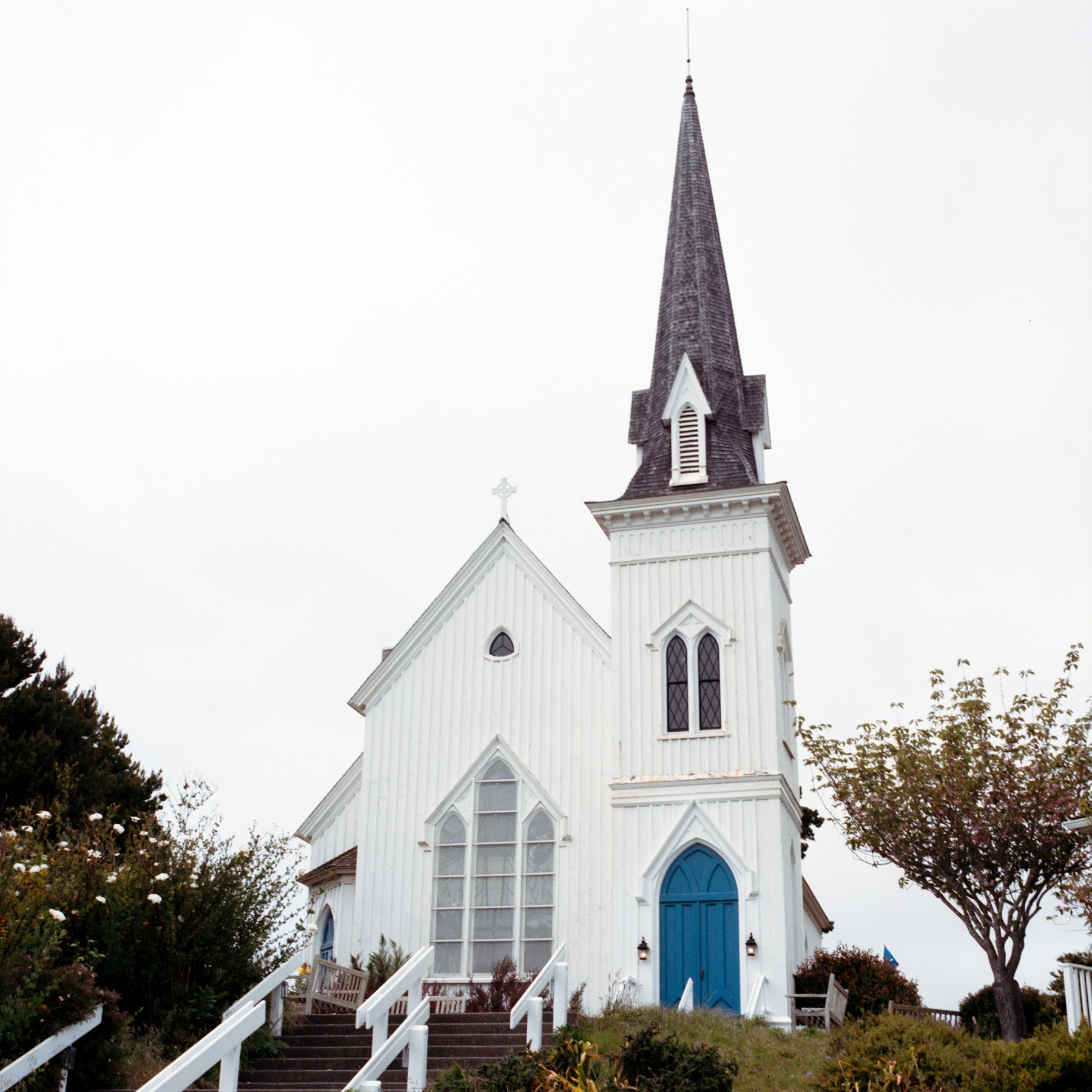 A white church with a tall steeple and a blue door